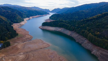 Wide angle photography of Lake Vidraru in Romania taken from a drone. Photography was shot from a higher altitude, and it can be seen the dried lake bed.