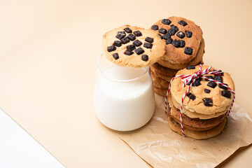 Chocolate chip cookie stack milk glass dessert snack sweet homemade bakery rustic tied ribbon parchment beige background dairy breakfast treat crumbly crispy