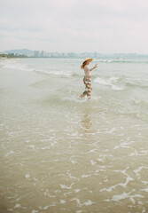 A girl in a national Chinese hat on the beach