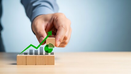 Hand placing a green dollar sign on a rising bar graph made of blocks.