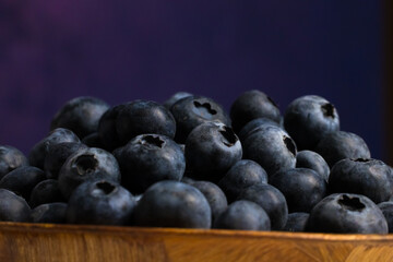 A close-up view of fresh blueberries in a wooden bowl.
