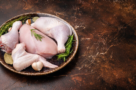 The promise of a perfect roast: prime raw poultry cuts rest with fragrant rosemary, thyme, and garlic on a deep, earthen plate, awaiting their culinary transformation.
