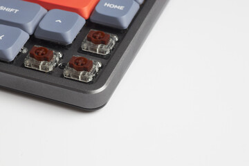 Close-up of colorful mechanical keyboard with removed keycaps showing brown switches on white background
