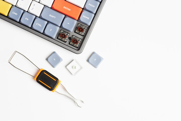 Mechanical keyboard with removed arrow keycaps, brown switches exposed, and keycap puller tool on white background
