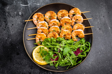 Gourmet seafood appetizer: prawn shrimp kebabs and fresh salad with lemon. Top-down view with vintage fork and copy space.