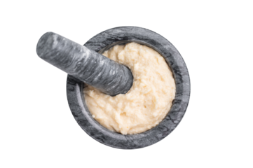 Freshly prepared cream sauce (horseradish or garlic aioli) being blended in a dark marble mortar and pestle. Homemade cooking process.