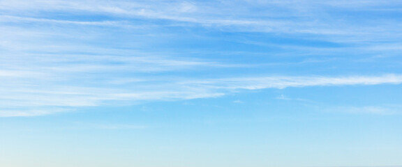 Fototapeta premium A wide view of a clear blue sky with wispy white clouds fading toward the horizon