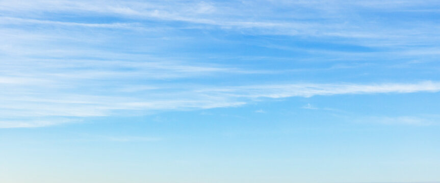 A wide view of a clear blue sky with wispy white clouds fading toward the horizon