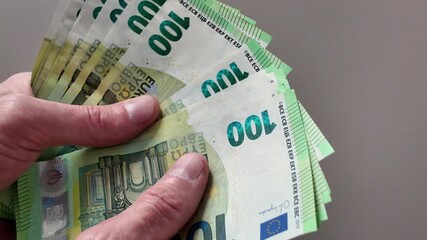 A man's hands count a wad of one hundred euro banknotes