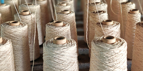 Naturl colored yarn spools in fabric production in textile factories.