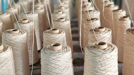 Naturl colored yarn spools in fabric production in textile factories.