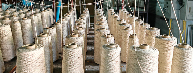 Naturl colored yarn spools in fabric production in textile factories.