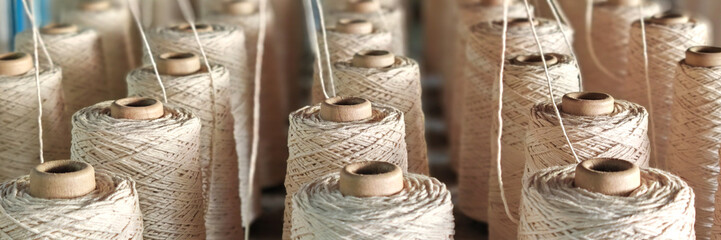 Naturl colored yarn spools in fabric production in textile factories.