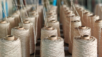 Naturl colored yarn spools in fabric production in textile factories.