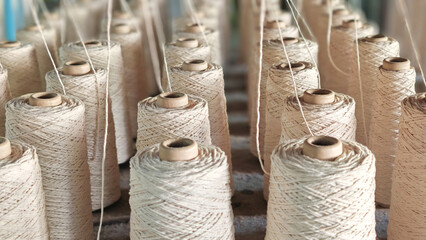 Naturl colored yarn spools in fabric production in textile factories.