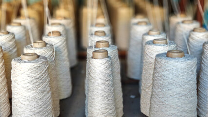 Naturl colored yarn spools in fabric production in textile factories.