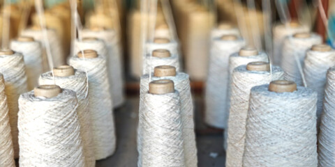 Naturl colored yarn spools in fabric production in textile factories.