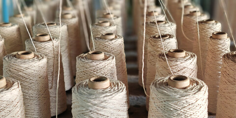 Naturl colored yarn spools in fabric production in textile factories.