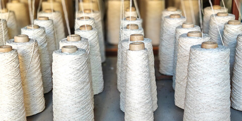 Naturl colored yarn spools in fabric production in textile factories.