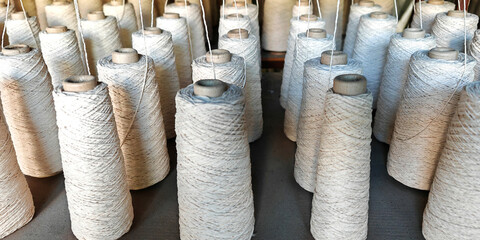Naturl colored yarn spools in fabric production in textile factories.