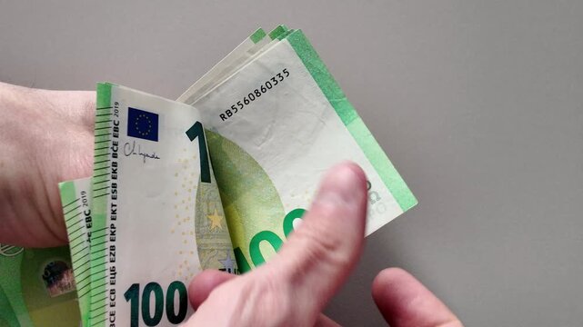 Close-up of a man's hands counting a stack of one hundred euro banknotes
