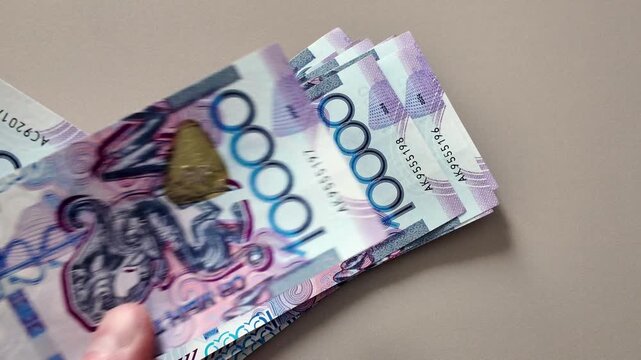 A man's hands count a stack of 10,000 Kazakhstani tenge banknotes