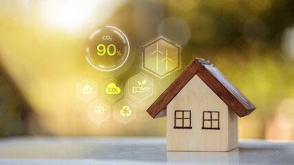 Wooden house model with virtual CO2 reduction interface and green energy icons.