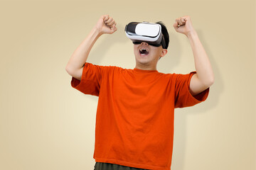 Excited young Asian man in an orange t-shirt wearing a virtual reality headset, looking upward and surprise, symbolizing the thrilling and immersive experience in studio background