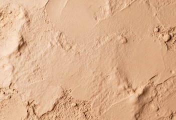 Fototapeta premium A close-up of a matte clay surface reveals a textured and gently porous background with subtle variations in light and shadows, creating an organic and earthy aesthetic