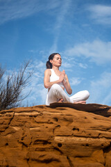woman sitting on a red rock meditating and practicing yoga