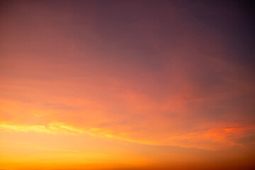 Colorful sunset sky with warm orange and purple clouds creating a dramatic natural background. Soft gradient evening light for nature, travel, landscape and abstract design use, beautiful dark sky