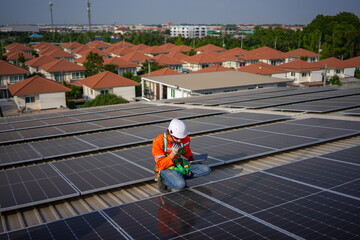 Blue collar worker is inspecting solar panel at rooftop of factory.
