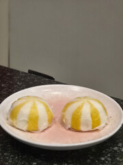Two delightful lemon mousse dome desserts on pink plate. This fancy gourmet pastry with yellow and white stripes, sweet, refreshing treat for cafe or restaurant menu