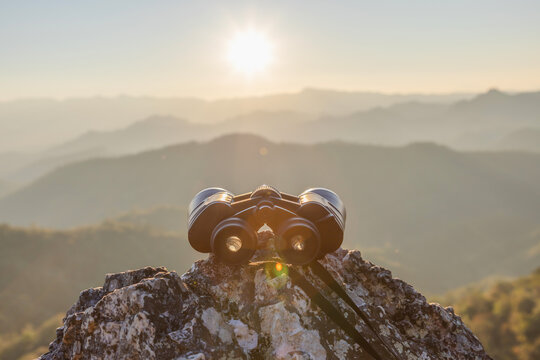 Binocular on top of rock Amazing wild nature view of layer of mountain forest landscape with sunset cloudy sky.