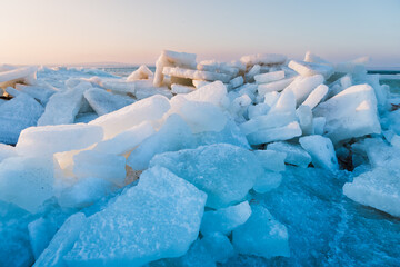 Ice chunks on a frozen lake at scenic sunrise with beautiful light and cold winter background.