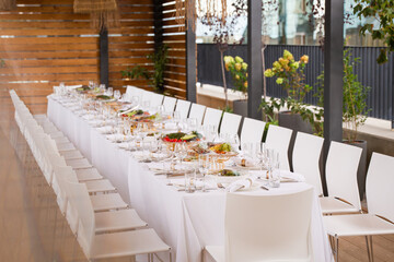 Wide shot of long set table on terrace with city view - elegant table setting for event