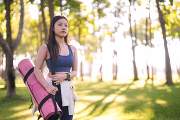 Asian woman fitness enthusiast prepare yoga session park promotes healthy active lifestyle wellness journey nature connection