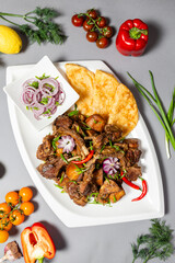 Top view of braised ribs with flatbread and onions on grey background. Complete meal