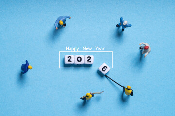 Miniature workers preparing the number blocks for 2026 create a playful scene symbolizing new year...