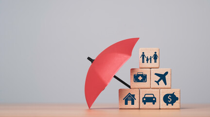 Wooden blocks with icons for family health travel home car and savings under an umbrella...