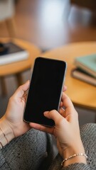Hands holding smartphone with blank screen in cozy indoor setting, suggesting technology use and quiet connection
