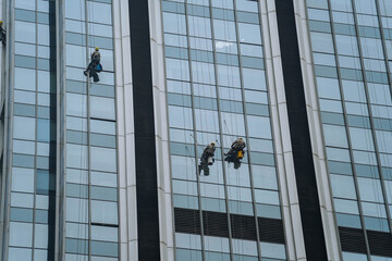 Professional Window cleaners at work washing windows on a high building. This is a risky job.