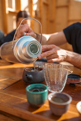 Close-up view of hot tea being gently poured from a clay teapot into a small cup during a traditional tea ceremony. Perfect for culture, wellness, and culinary themes.
