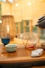 Close-up view of hot tea being gently poured from a clay teapot into a small cup during a traditional tea ceremony. Perfect for culture, wellness, and culinary themes.