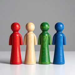 Four wooden figurines of varying colors stand in a row against a neutral backdrop.  Each figure has a simple, upright posture