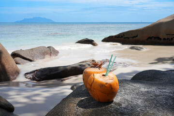 Drinking a fresh coconut with a straw on a tropical beach in the Seychelles