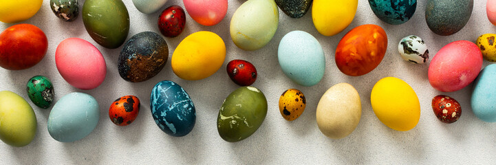 A collection of Easter eggs in bright colors and patterns is displayed on a light surface, capturing the festive spirit of Easter celebrations and springtime joy, banner