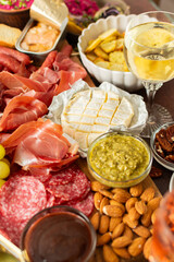 Gathered around a beautifully arranged charcuterie board filled with assorted cheeses, delicious sausages, creamy hummus, and fresh grapes. Perfect for a small gathering