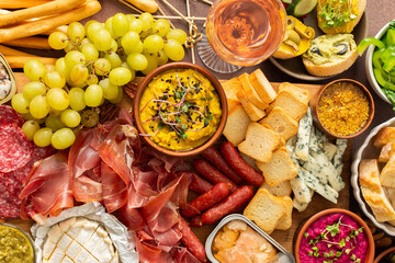 Taste a variety of flavors with this charcuterie board filled with cheese, sausages, hummus, nuts, and fresh sandwiches, perfect for any gathering