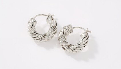 Silver twisted earrings polished shiny reflective delicate curved design on plain white background